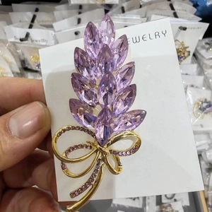 Macro shot of purple crystal wheat ear brooch with gold bow detailing and inlaid stones