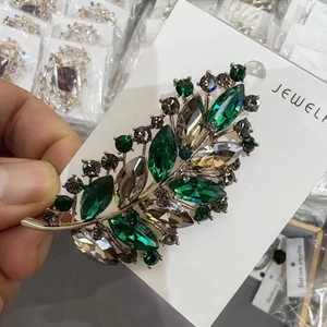 Detailed view of luxury leaf brooch with green marquise crystals and gold plating