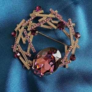 Broche anneau doré élégante avec cristaux violets et gemme ovale sur soie bleue
