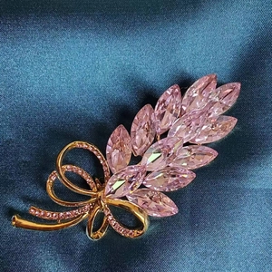 Elegant gold wheat ear brooch with pink crystals and ribbon bow on silk background