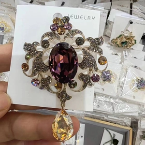 Dettaglio di spilla barocca vintage con cristallo viola e pendente color champagne