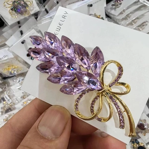Macro detail of wheat brooch with purple marquise crystals and golden bow tie knot