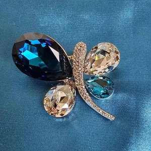 Macro shot of butterfly brooch with blue and champagne crystals on a textured blue fabric