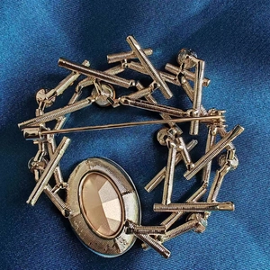 Broche anneau dorée élégante avec cristal champagne sur fond de soie bleue