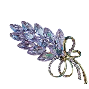 Elegant gold wheat brooch with purple crystals and sparkling bow on a white background