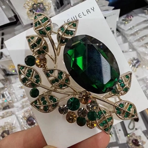 Vintage emerald green crystal leaf brooch in gold finish with oval faceted gemstone