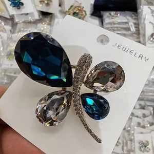 Detailed macro of a silver butterfly brooch featuring blue and grey teardrop gemstones