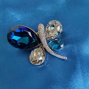 Macro shot of butterfly brooch with blue and champagne crystals on silk satin