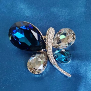Detailed view of butterfly brooch with blue crystals and pavé set silver tone wings