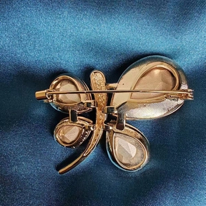 Elegant gold dragonfly brooch back view showing secure safety pin and metallic texture