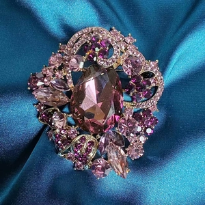 Macro shot of luxury drop-cut purple crystal brooch with marquise stones on green silk