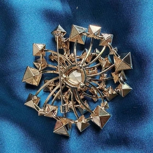 Dettaglio della chiusura di sicurezza e del retro placcato in oro della spilla fiore