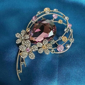 Vue détaillée d'une broche fleurie en cristal avec pierre violette sur fond en soie