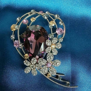 Broche fleur élégante avec cristal goutte violet et strass colorés sur de la soie bleue