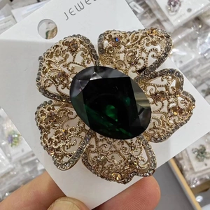 Detail of vintage emerald flower brooch with crystal accents and golden hollow petals