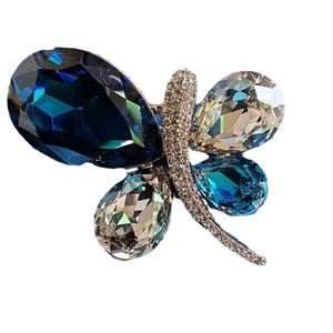 Elegant butterfly brooch with deep blue and champagne crystals on a white background