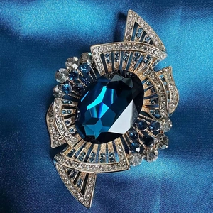 Macro shot of royal blue oval crystal brooch with gold filigree and sparkling rhinestones