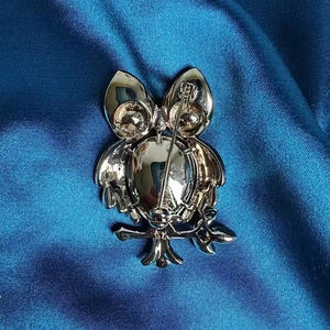 Détail de l'arrière de la broche hibou montrant le fermoir sur un tissu en soie bleu foncé