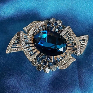 Vintage gold brooch featuring a royal blue oval stone and geometric crystal design
