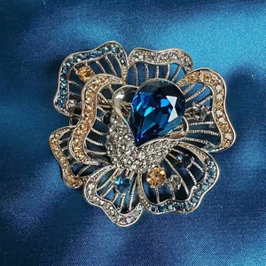 Macro shot of a blue crystal flower brooch featuring intricate petals on navy silk fabric
