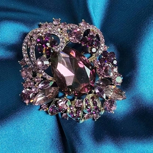 Detailed close-up of a luxury purple crystal flower brooch with marquise stones and gold plating