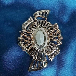 Vintage gold-plated brooch with blue satin background showing the secure back clasp