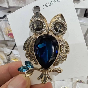 Gros plan détaillé d'une broche hibou avec pierres précieuses bleu foncé et cristaux