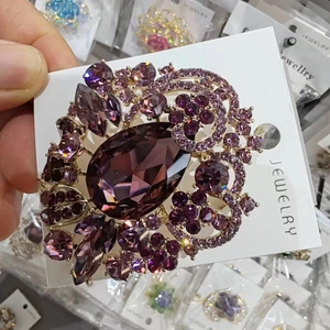 Detailed close-up of a luxury purple crystal brooch featuring a teardrop center stone
