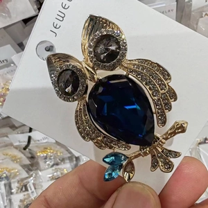 Vue détaillée de la broche hibou avec cristal bleu foncé en forme de poire et métal doré