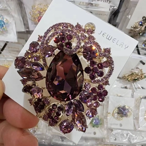 Detailed close-up of a luxury purple crystal brooch featuring a teardrop center stone
