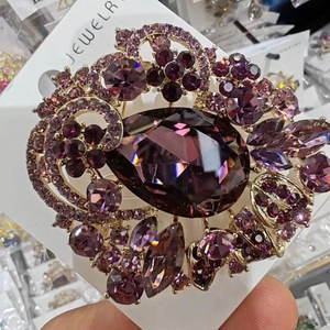 Detailed macro view of a vintage purple teardrop crystal brooch with golden filigree