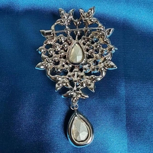 Broche vintage en argent avec cristaux bleu clair sur texture de tissu en soie bleue