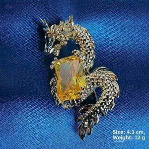 Macro view of a gold dragon brooch featuring a large yellow gemstone on blue velvet fabric