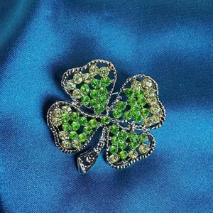 Broche trèfle à quatre feuilles émeraude élégante avec cadre argenté sur soie bleue