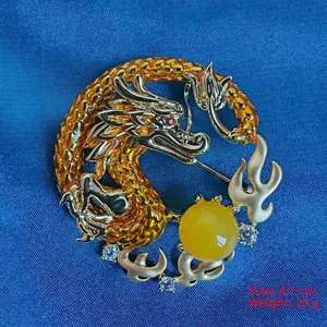 Detailed macro view of a golden dragon brooch with red gemstone eyes and micro zircon inlay