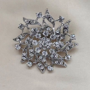 Elegant silver floral brooch with shimmering crystals in a radiant snowflake design