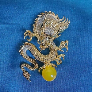 Detail of a golden dragon brooch featuring micro-set white zircons and a yellow gemstone bead
