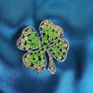 Vue détaillée de la broche trèfle à quatre feuilles pavée de cristaux vert émeraude