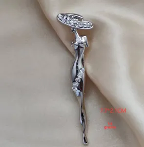 Détail d'une broche silhouette femme argentée avec strass sur satin, taille 7,7x2,1 cm