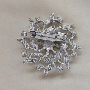 Silver alloy brooch featuring a hollow sunburst design with a secure rotating safety pin