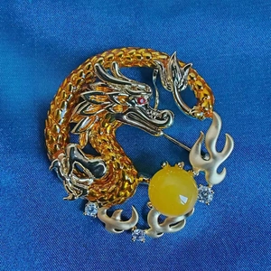 Detailed view of a Chinese dragon brooch with amber scales and micro-set cubic zirconia stones
