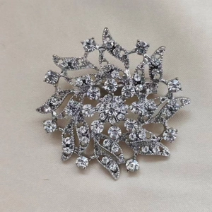 Detail shot of a silver starburst brooch with multi-layered rhinestones and center crystal