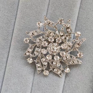 Macro view of silver starburst flower brooch with radiant rhinestones on velvet tray