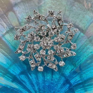 Macro shot of silver radial brooch featuring intricate sparkling rhinestones on blue base
