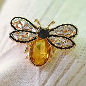 Broche abeille dorée élégante avec pierre jaune et émail noir sur tricot blanc cassé