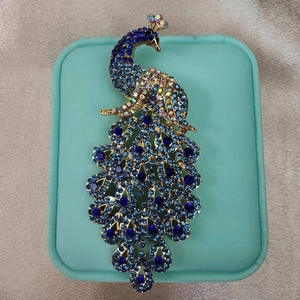 Close-up of golden peacock brooch with sparkling blue rhinestones on jewelry box