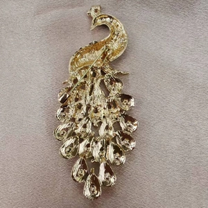 Exquisite golden peacock brooch with secure pin clasp on luxury champagne silk fabric