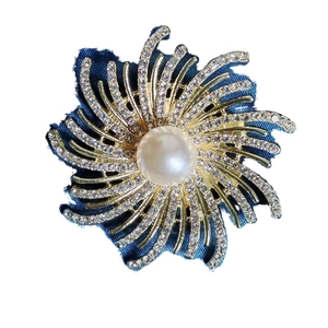 Broche fleur radiale avec perle blanche et pétales en strass sur tissu bleu