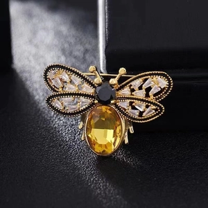 Détail macro de broche abeille avec ailes dorées et corps en pierre gemme jaune