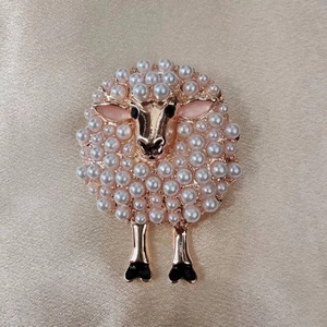 Detailed view of a sheep brooch featuring white pearls and rose gold plating on silk